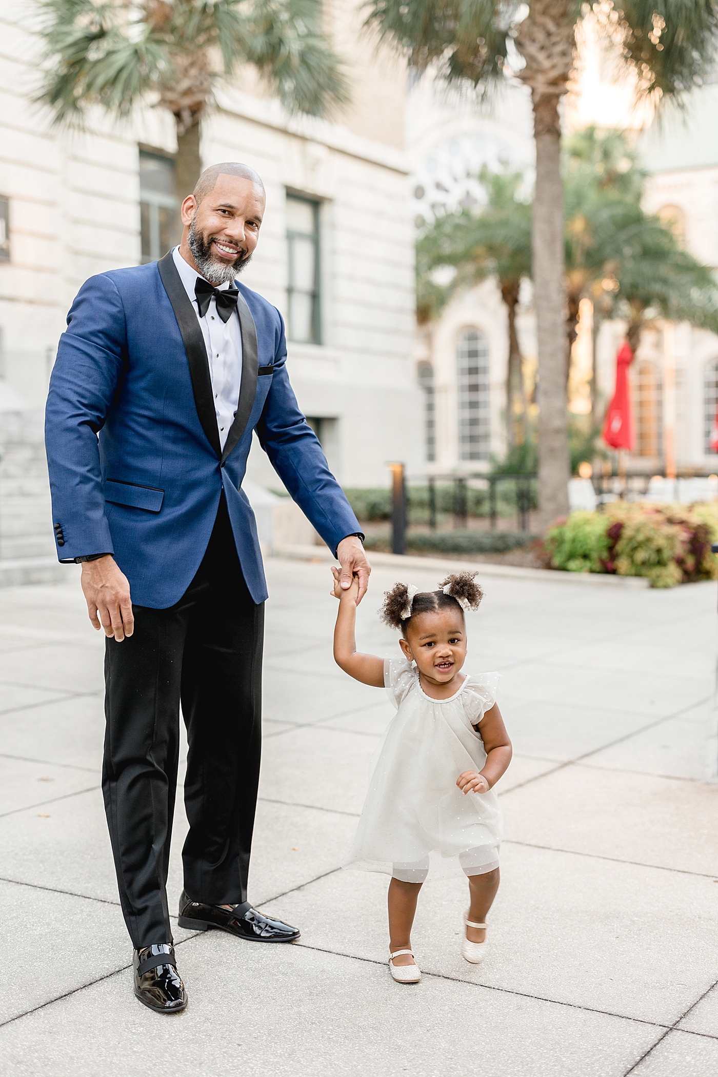 Two year old little girl holding her Dad's hands walking. Photos by Brittany Elise Photography.