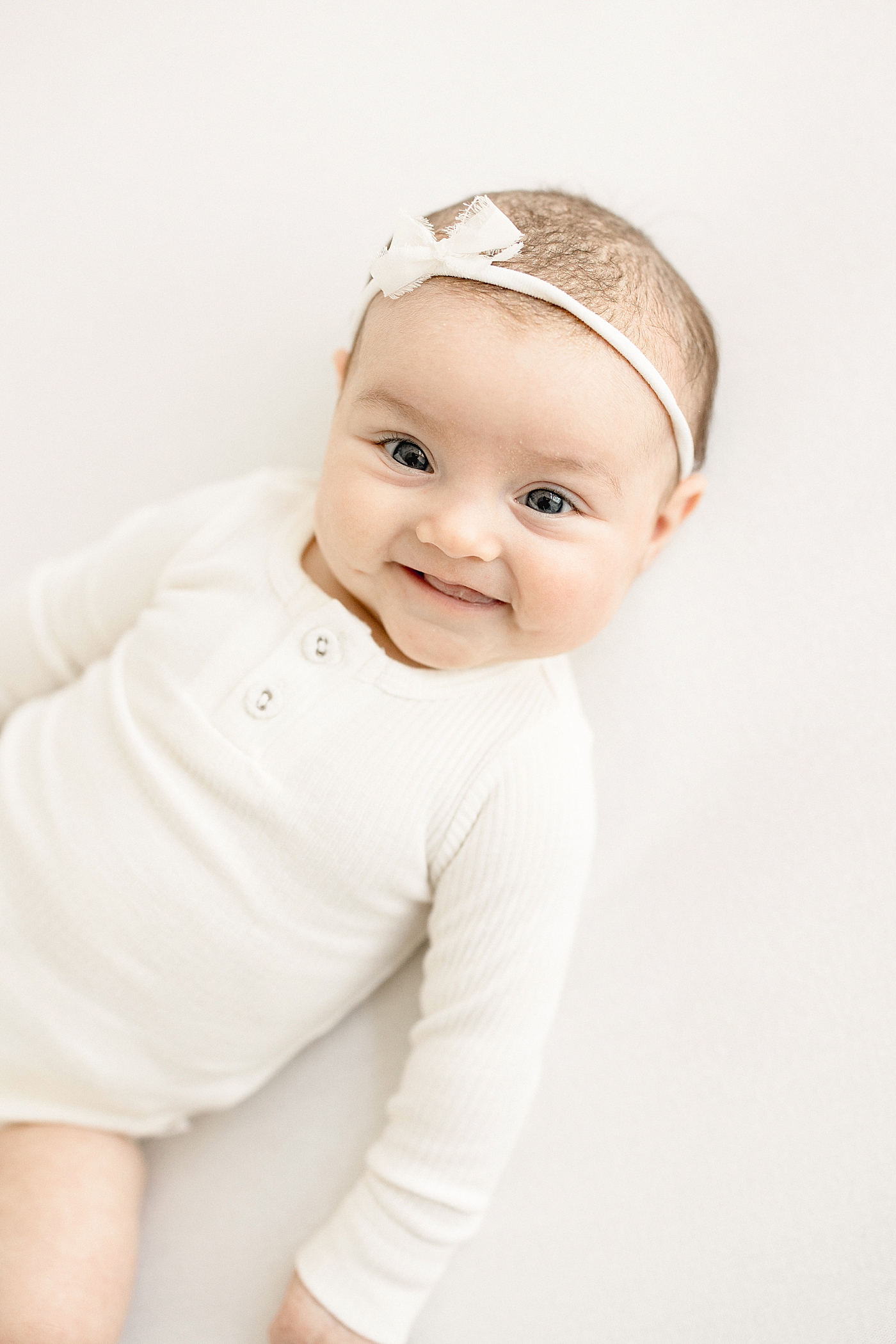 3 month old baby girl smiling during milestone session. Photo by Brittany Elise Photography.