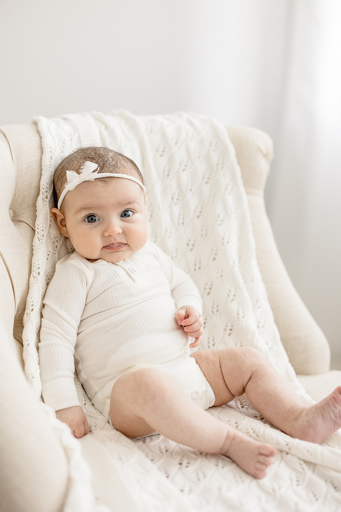 Baby girl sitting up in chair during milestone session. Photo by Brittany Elise Photography.