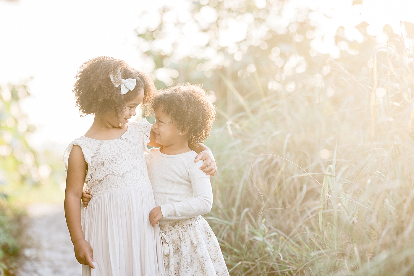 Sisters standing together with their arms around each other. Photo by Brittany Elise Photography.