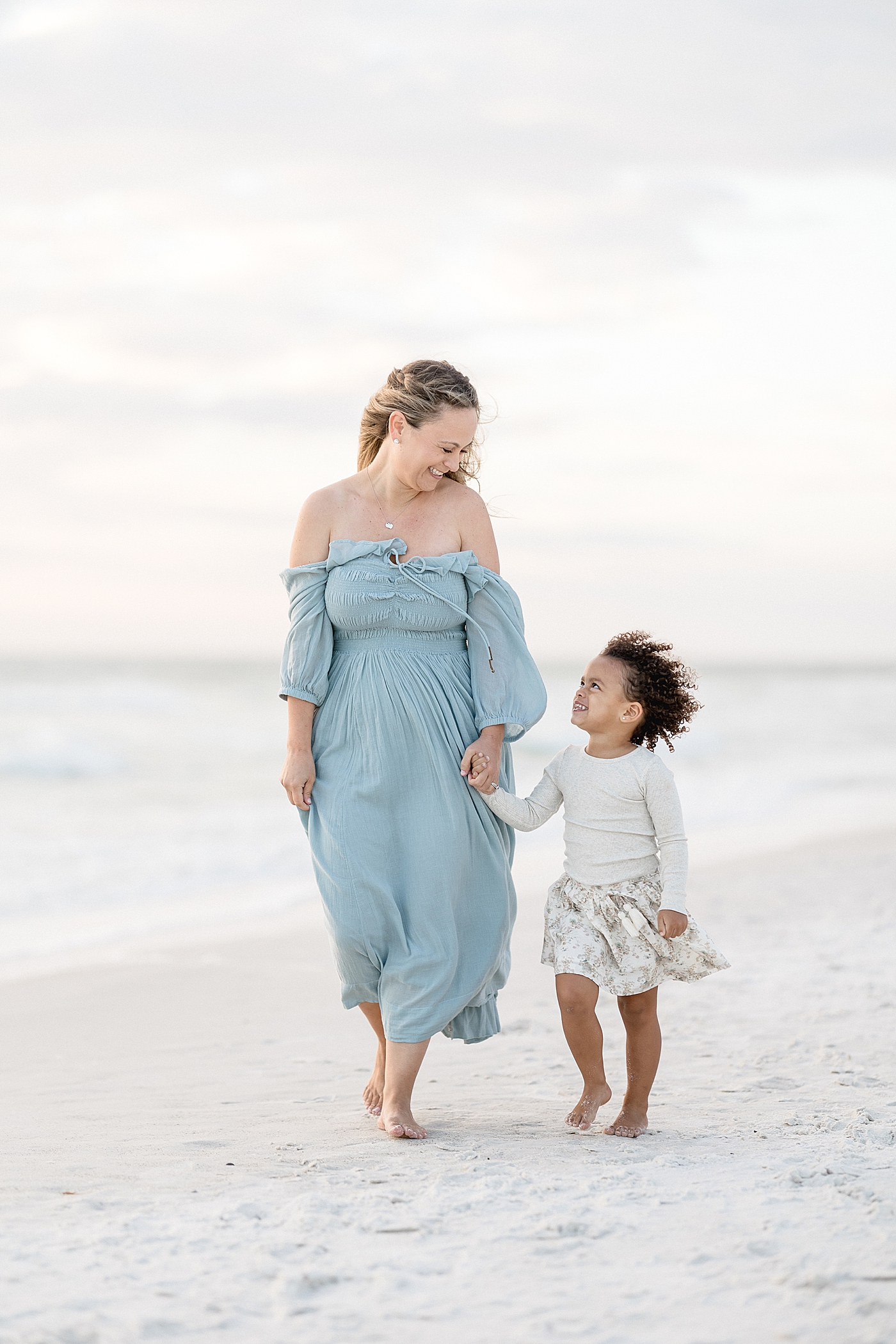 Mom walking with her daughter on the beach. Photo by Brittany Elise Photography.