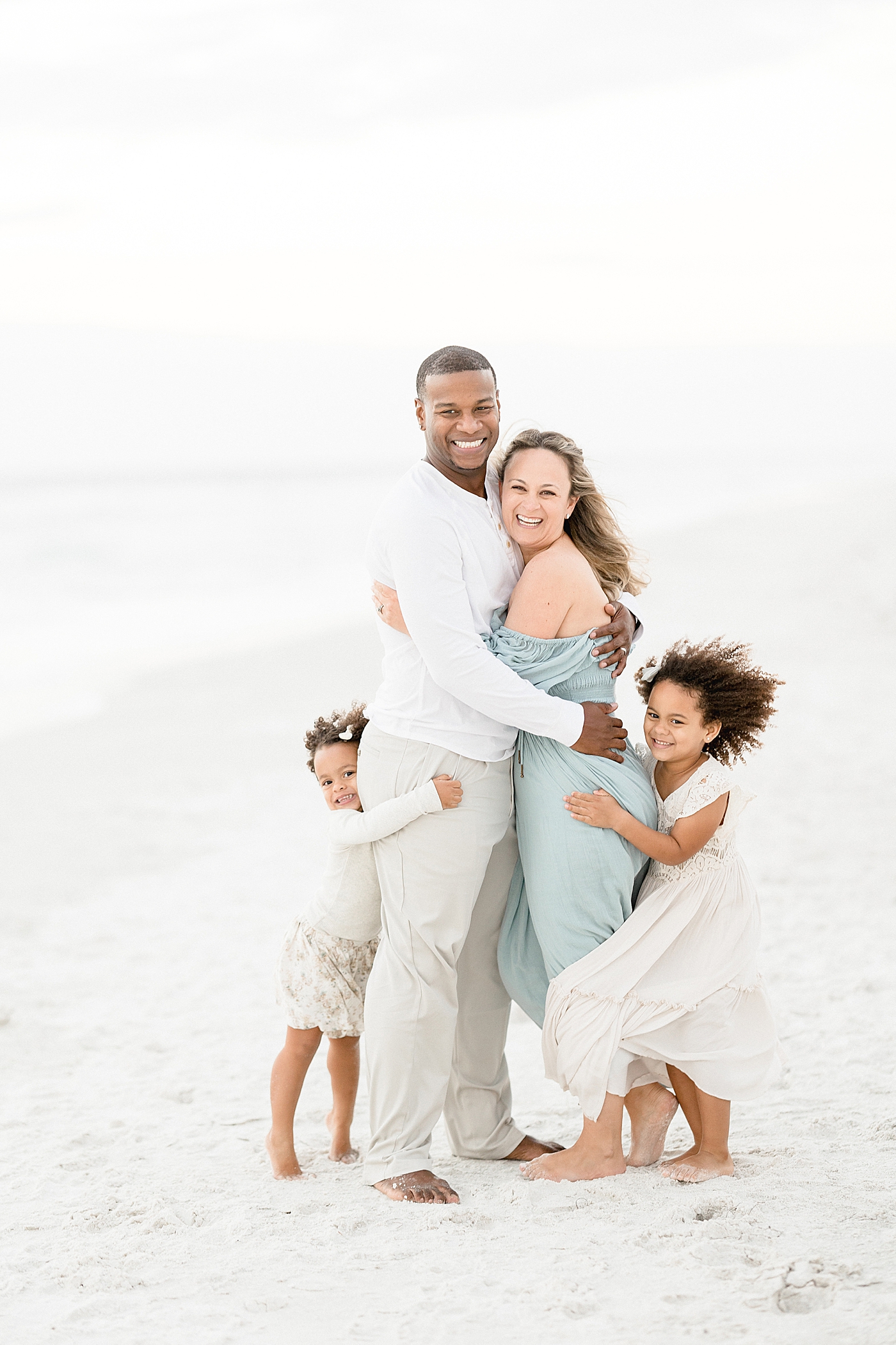 Girls hugging Mom and Dad during family session on the beach with Brittany Elise Photography.