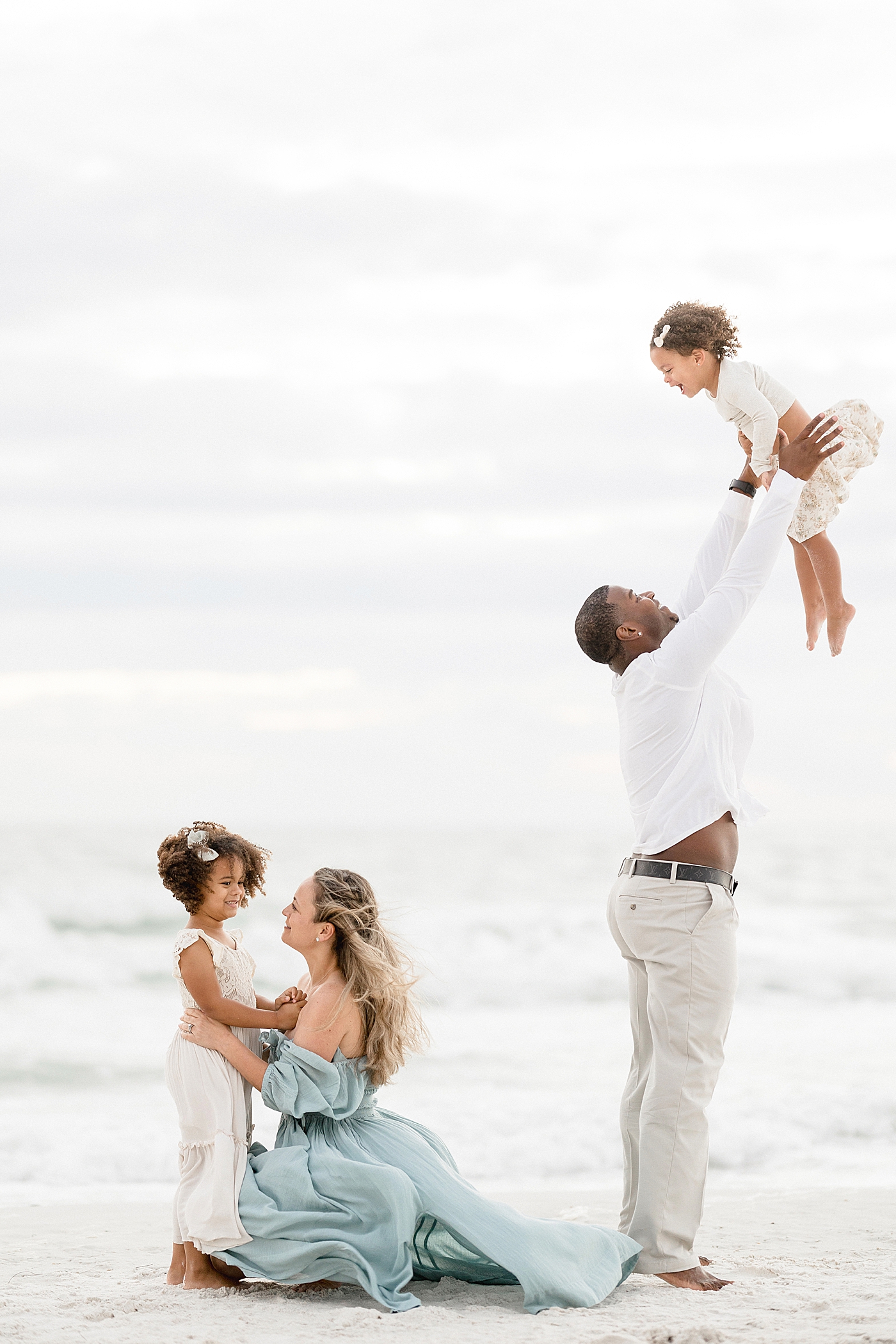 Parents playing with their two daughters on the beach during family photoshoot. Photo by Brittany Elise Photography.