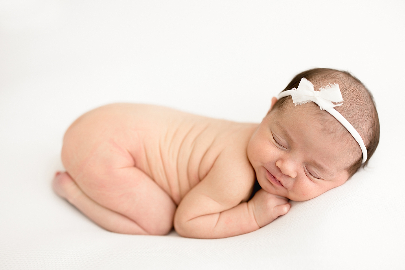 Baby girl curled up on her belly for newborn portraits with Brittany Elise Photography.