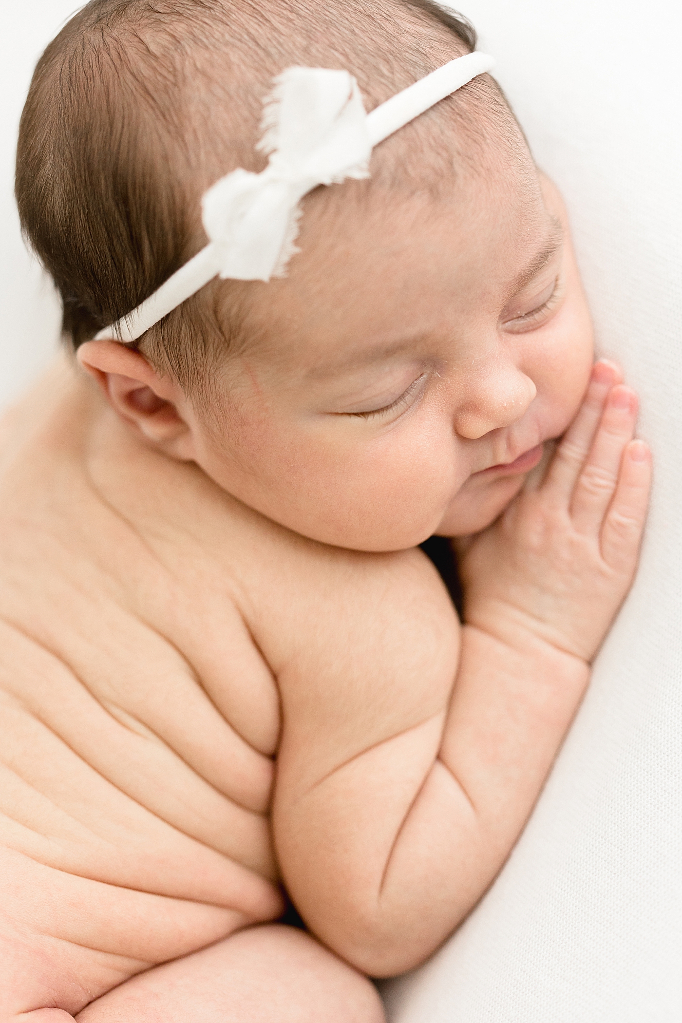 Newborn baby curled up showing off her rolls! Photo by Brittany Elise Photography.