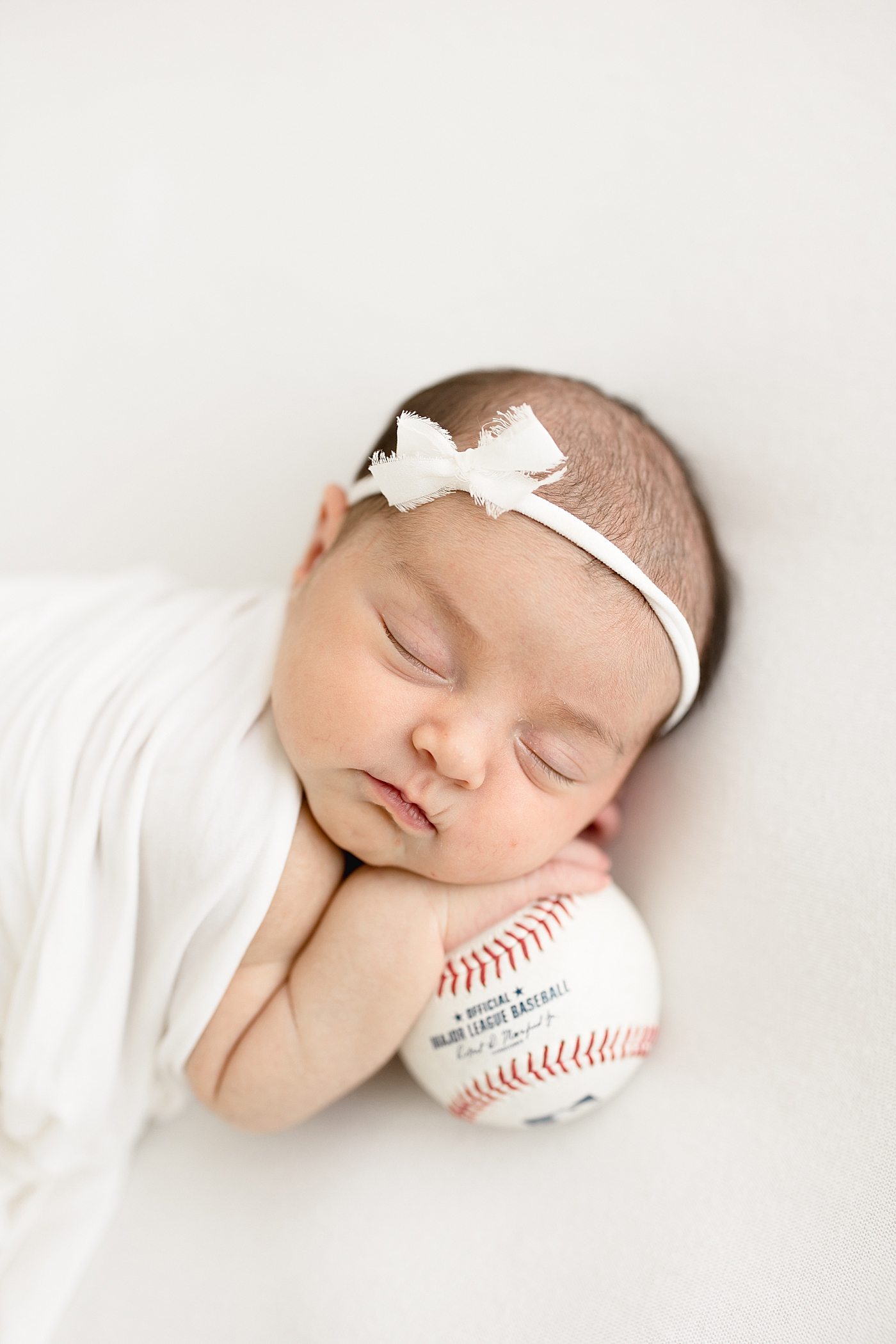 Newborn posing on baseball. Photo by Brittany Elise Photography.