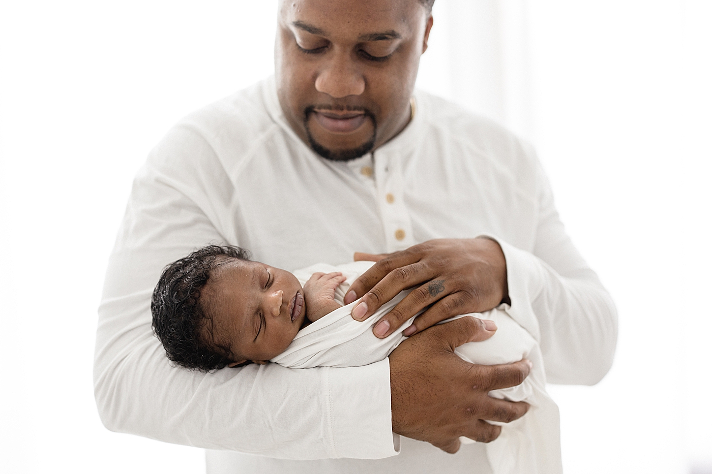 Dad holding son in his arms during newborn session in Tampa studio. Photo by Brittany Elise Photography.