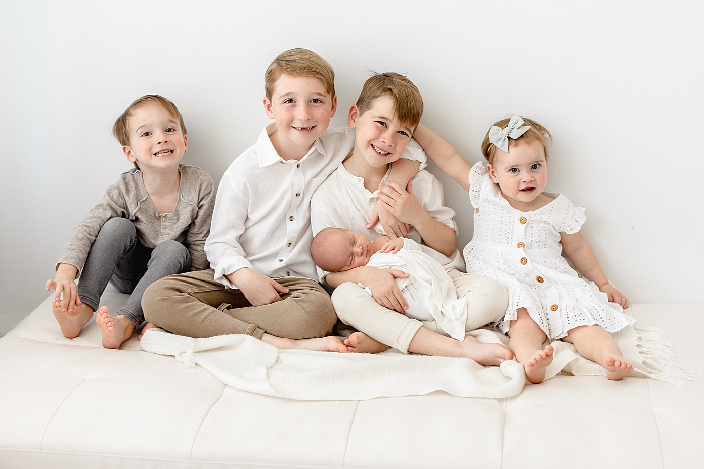 Older siblings holding their baby brother for newborn photos. Photo by Brittany Elise Photography.