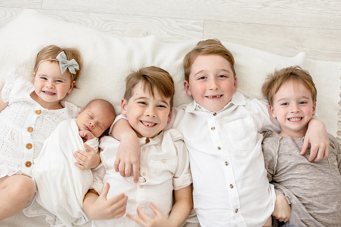 Four older siblings laying with their baby brother. Photo by Brittany Elise Photography.
